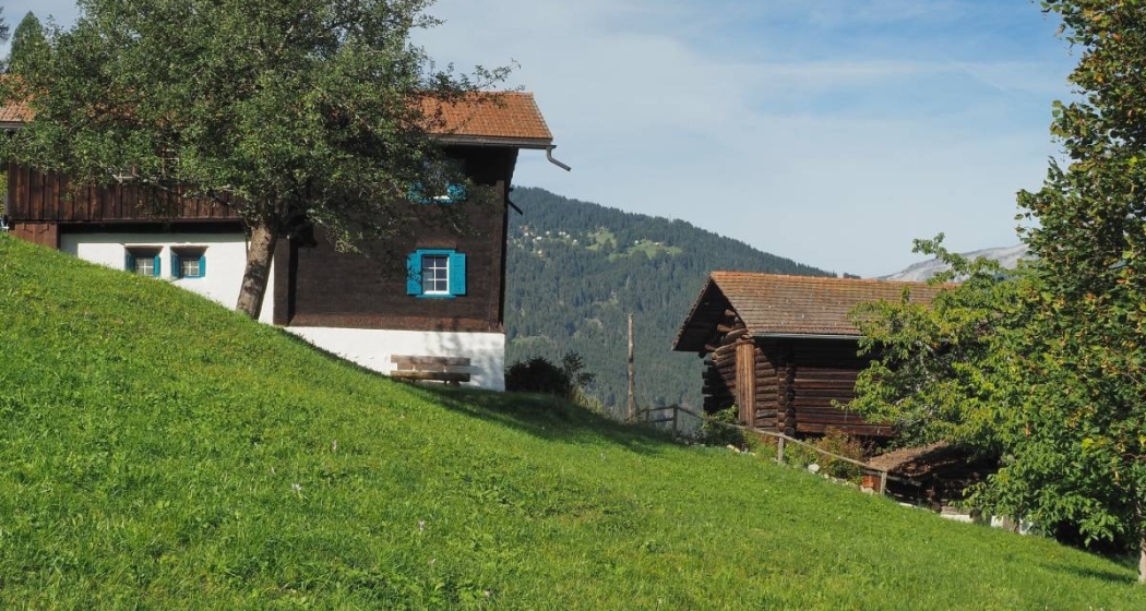 Vorbei an den sonnengebräunten Holzhäuser von Praden Vorbei an den sonnengebräunten Holzhäuser von Praden